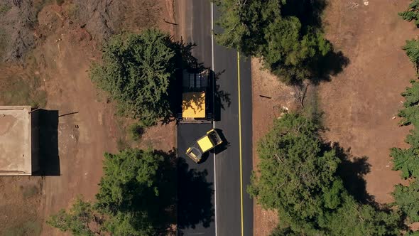 Road roller pressing fresh put Asphalt on a new road, Aerial follow footage.