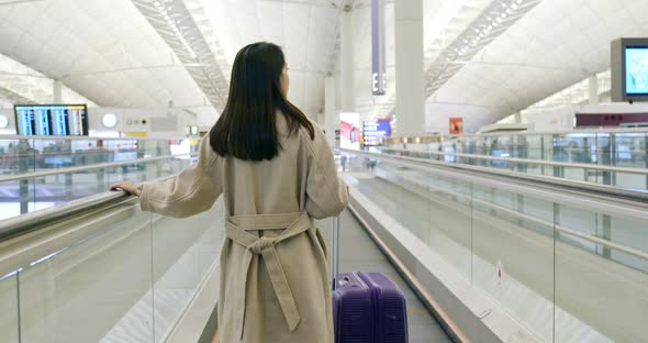 Back View of Businesswoman on Travelator with Her Luggage at Airport 