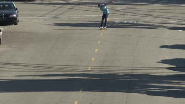 A young man skateboarding in the middle of the street.