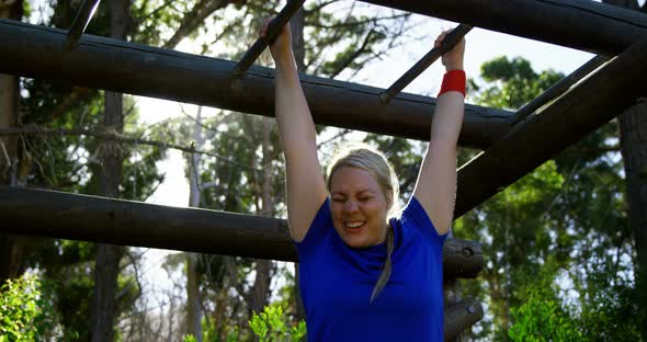 Determined woman exercising on monkey bar during obstacle course