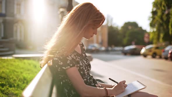 Foxy Dreamy Young Girl Sitting Writing Notes with Sunlight on Hair in Slowmotion