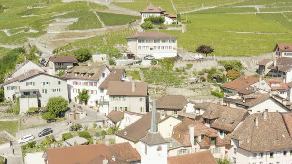 Aerial orbit around bell tower of typical village (Riex) in Lavaux vineyard - Switzerland