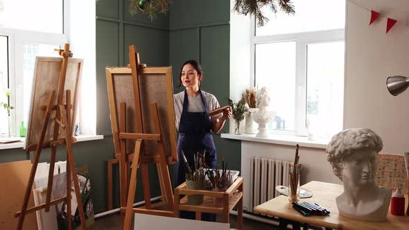 Art Studio  Young Woman Puts a Canvas on an Easel  Picks Up a Palette and Starts Painting