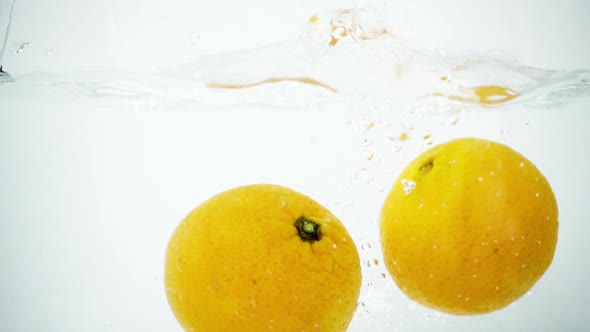 Two Tangerines Being Splashed into Water in Super Slow Motion