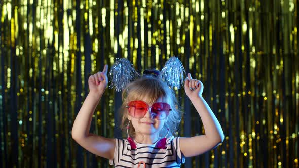 Stylish Teenager Kid Girl Standing on Backlit Blue Neon Lights and Points at Blank Space Agree Sign