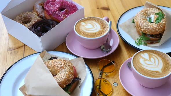 Trendy Breakfast With Bagels, Donuts And Coffee On Wooden Table