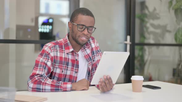 African Man Making Video Chat on Tablet in Office