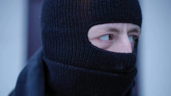 Closeup Face of Suspicious Caucasian Man in Ski Mask Looking Around and Looking at Camera with Brown