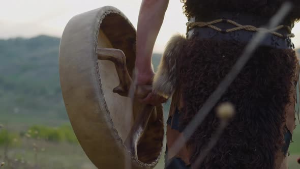 Shaman Walks Holding Ritual Drum Along Hilly Valley