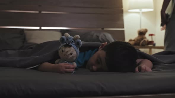 Mother Turning off Light for Sleeping Son