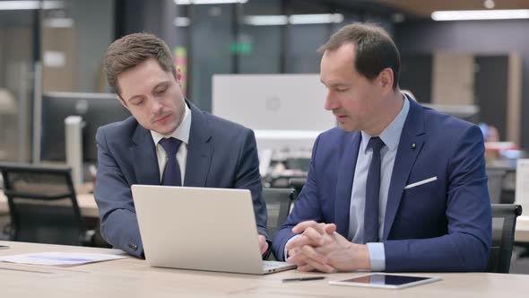 Businessman and Colleague Discussing on Laptop