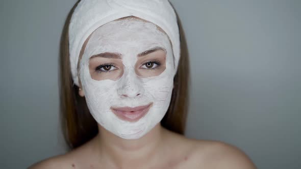 Girl with Cosmetic Mask on Face Looks at Camera and Down on Naked Shoulder