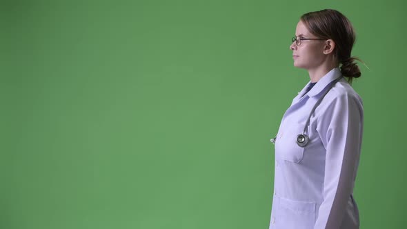 Profile View of Young Beautiful Woman Doctor Against Green Background