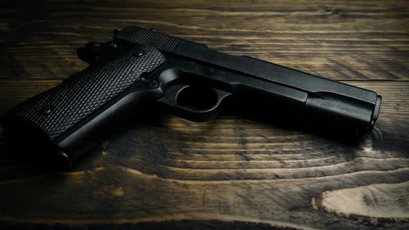 Gloved Hand Picks Up Hand Gun alt