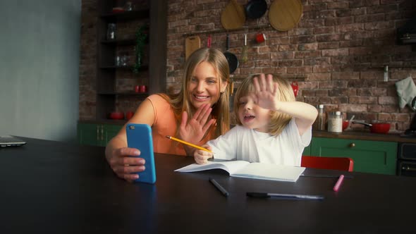 Smiling Mommy and Her Little Boy are Enjoying Online Video Call on Smartphone While Doing Homework