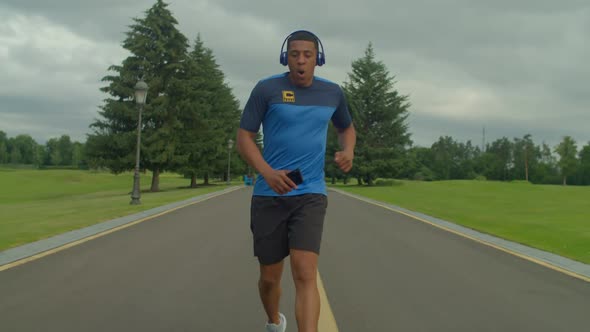 Active Sporty Fitness Black Male Jogger in Headphones Taking Break During Run