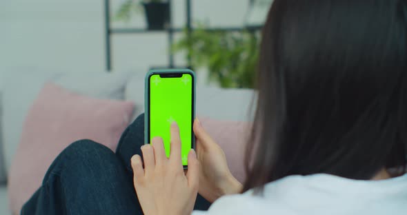 Rear View of Woman in Modern Room Sitting on Couch Using Phone with Green Screen Mockup Chroma Key