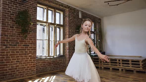 Young Slim Ballerina Dressed in white tutu Trains Gracefully in Pointe Ballet