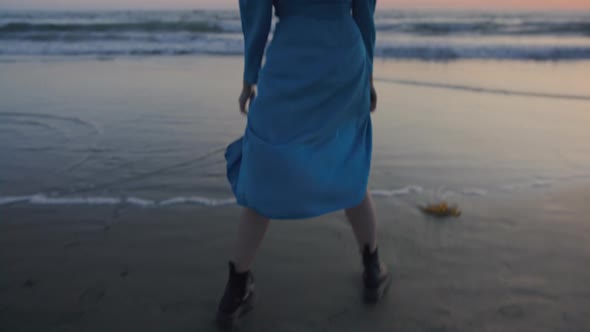 Woman on Sandy Beach Walking in Boots and Dress