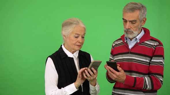 An Elderly Couple Works on Two Smartphones - Green Screen Studio