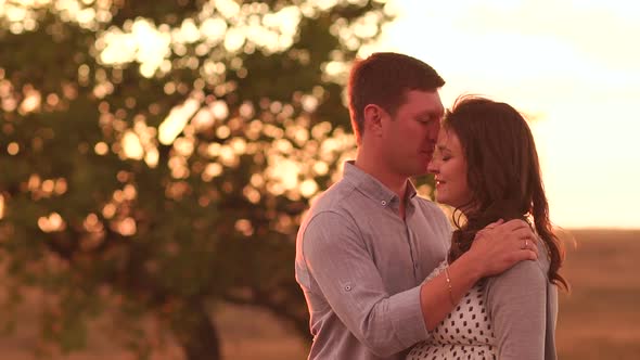 Portrait of a Happy Pregnant Couple in a Field at Sunset