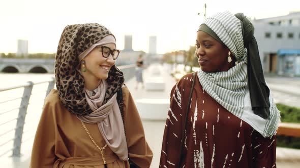 Young Muslim Women Walking on Embankment