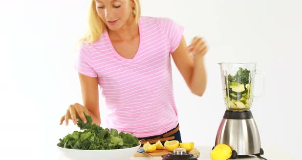 Woman preparing vegetable smoothie against white background