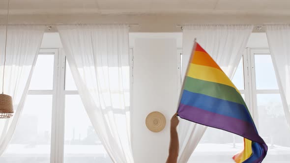 Rainbow LGBT Flag in Hand and Waving on Sunset in Sunny Rays