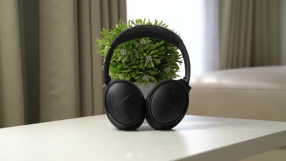 close up headphone on the white table with flower vase behind