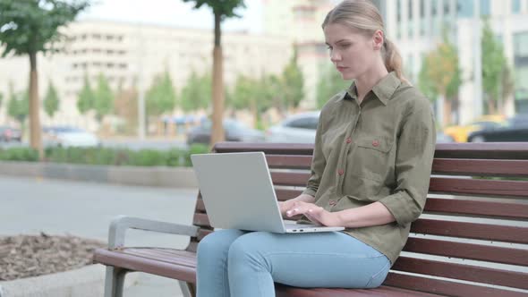 Woman Reacting to Loss on Laptop while Sitting Outdoor on Bench