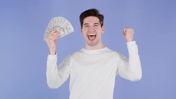 Happy Excited Man with Cash Money  USD Currency Dollars Banknotes on Violet Wall