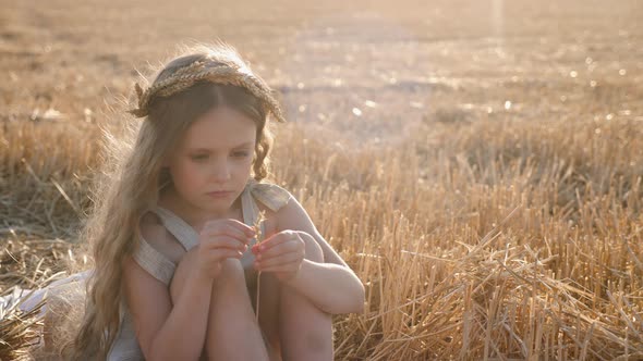 Serious Sad Girl a Child Sit on a Wheat Mown Field