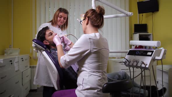 Woman Dentist Polishing Client's Teeth at Visit