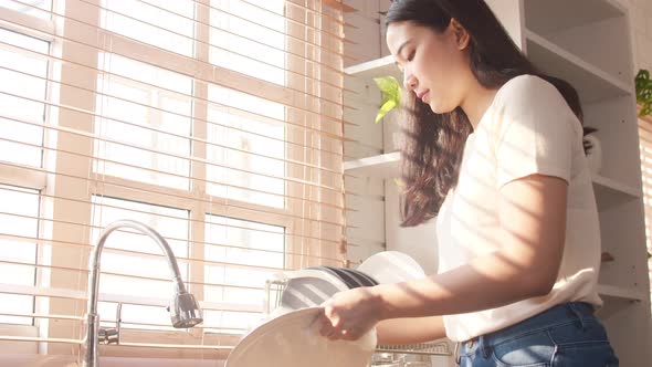 Asia lady washing dishes while doing cleaning in the kitchen at house.