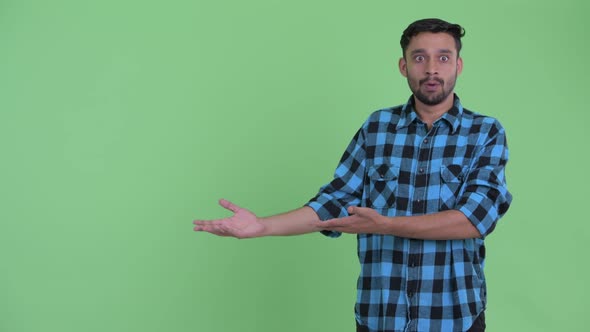 Happy Young Bearded Persian Hipster Man Showing Something and Looking Surprised