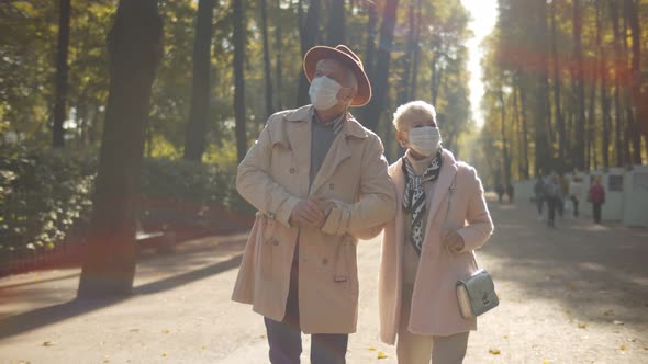 Mature Couple Wearing Sterile Face Masks Walking in Autumn Park