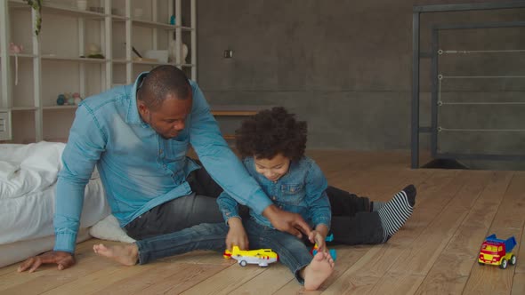 African Father and Son Playing with Toys on Floor