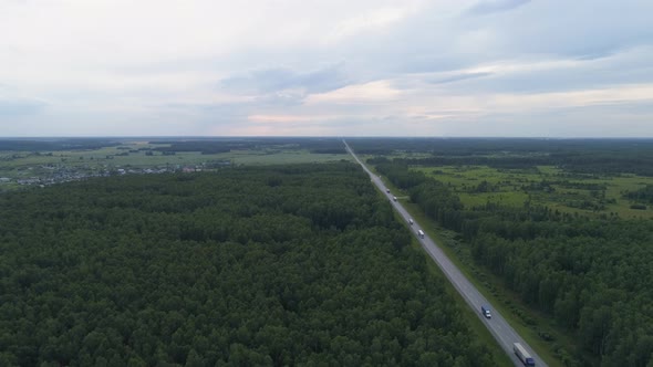 Drone aerial shot of a trucks and cars on the summer forest road near hills, Evening 08