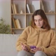 Young Woman Checking News on Smart Phone Sitting on a Couch at Home in the Day - VideoHive Item for Sale