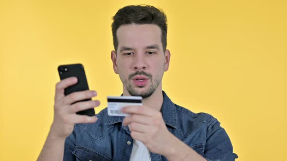 Portrait of Young Man Making Online Payment on Smartphone, Yellow Background