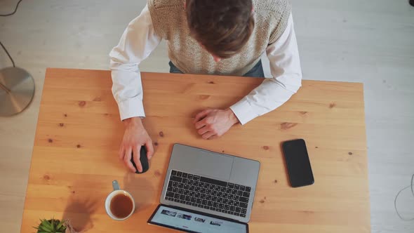 Man Sits at a Desk and Uses a Laptop Surfing the Internet a Man Visits Online Stores Spending Time