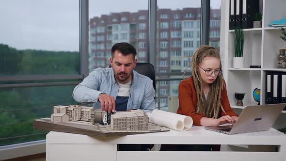 Male and Female Colleagues which Working Together with Model of New Buildings