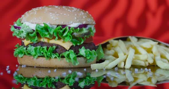 Freshly Cooked Hamburger and Fried French Fries on a Red Reflected Flame Background.