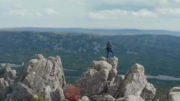 The Man on the Top of the Cliff Raises His Hands To the Sky