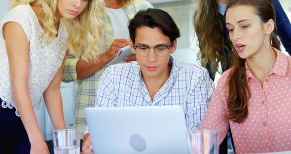 Colleagues discussing over laptop at table