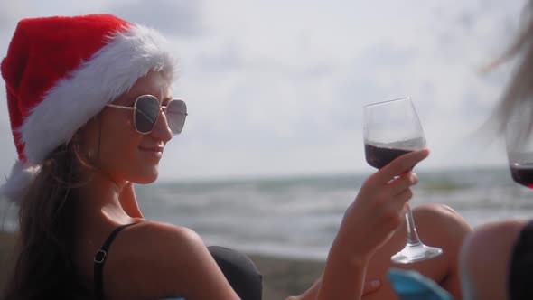 Two women in santa clasus hat, at Christmas, on beach, by sea