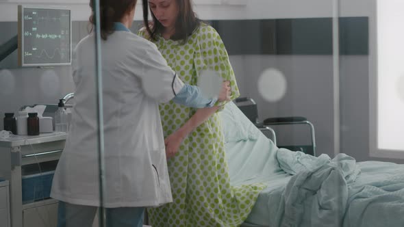 Black Asisstant with Practitioner Doctor Helping Patient to Stand Up From Bed