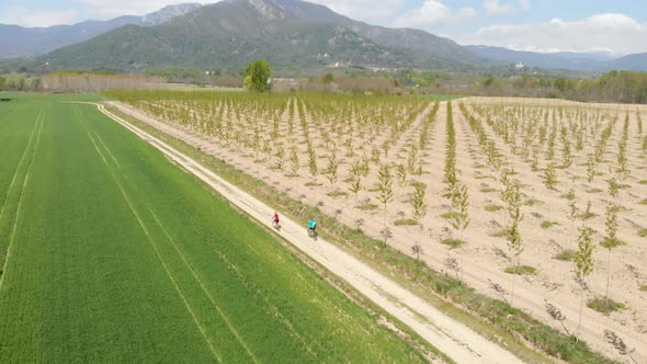 Couple having fun by riding mountain bike on dirt road in sunny day, scenic landscape of snowcapped