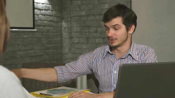 Handsome Young Businessman Showing Diagrams To His Colleague