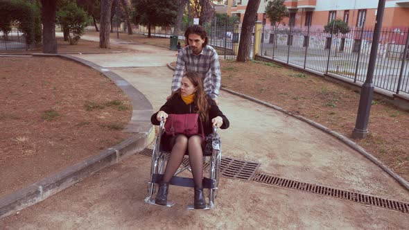 disabled person - man pushes his girlfriend with paraplegia in a garden